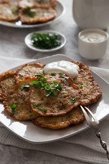Vegetable pancakes with sour cream on white plate