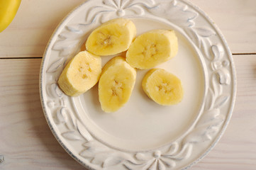 The banana is peeled and cut into several slices. On a white plate. View from above. Close-up. Macro shooting.
