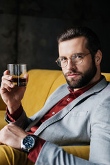 portrait of stylish bearded man holding glass of whiskey