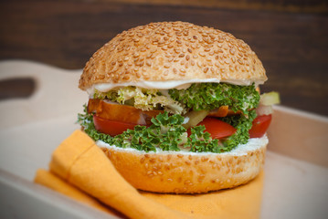 Homemade Hamburger in Wooden box, with fresh Vegetables on rustic Wooden Background with copy Space. Orange Napkin.