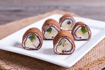 Chocolate pancakes rolls with curd and fruit ready for breakfast for the whole family