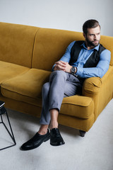 stylish man sitting on yellow sofa