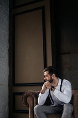 handsome thoughtful man sitting in armchair