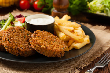Serving of falafel and chips served on a black plate with sauce.