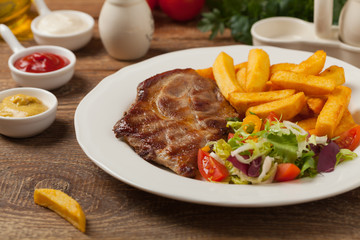 Grilled pork neck served with French fries and salad.