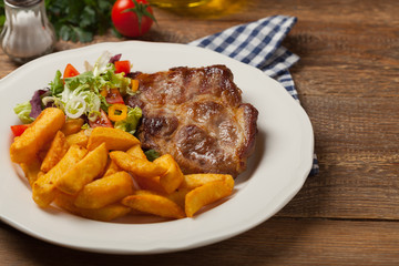 Grilled pork neck served with French fries and salad.