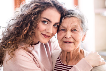A teenage girl with grandmother at home, hugging.