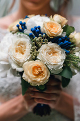 wedding bouquet of white peonies and yellow roses in the hands of the bride close-up