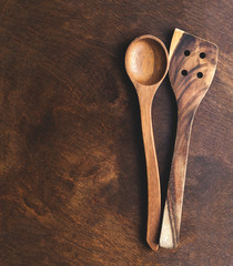Kitchen wooden utensils over vintage wooden background with copy space, top view. Spoon and skimmer.