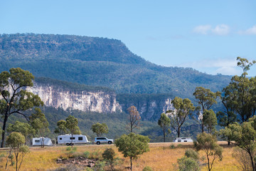 Car towing a caravan with mountains in the background
