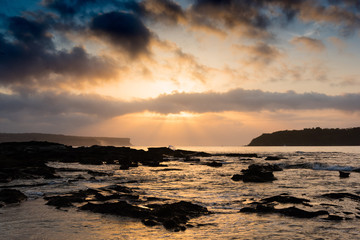 Orange sunrise peeking through clouds