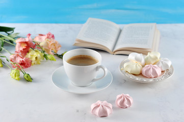 Sweet dreams ... A book, a cup of coffee, meringue, flowers. Romantic and gentle compassion. Light background. Close-up.