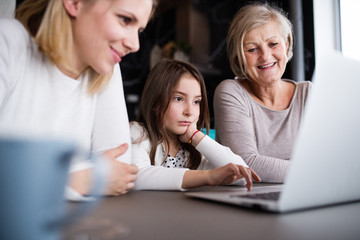 A small girl with mother and grandmother at home.