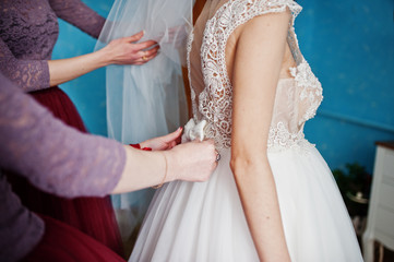 Obraz na płótnie Canvas Bridesmaids helping bride to get ready for her wedding ceremony.