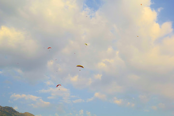 Paragliders in the summer sky. Paragliding photo for background. Summer extreme sports. Mountains and blue sky with clouds. Colorful lifestyle.