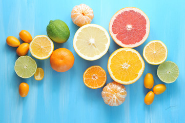 Collage of citrus. In the frame, lime, kumquat, mandarin without peel, halves of orange, mandarin, lemon, grapefruit, lime. Blue wood background. Close-up. View from above.