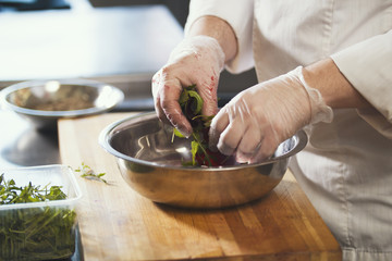 Chef preparing a salad in the kitchen of the restaurant, close up