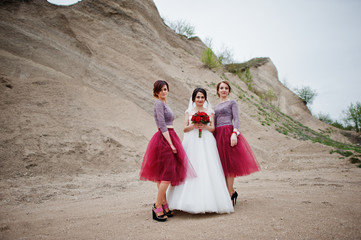 Bride posing with her bridesmaids in sand quarry on her wedding day.
