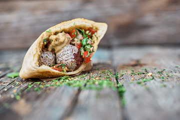 Falafel and fresh vegetables in pita bread on wooden table. Healthy lifestyle. Selective focus.