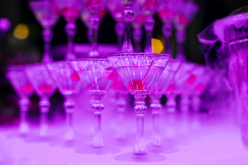 Martini glasses with sweet cherry close - up with pink illumination