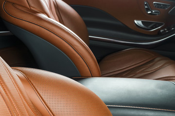 Modern Luxury car inside. Interior of prestige modern car. Comfortable leather brown seats. Orange perforated leather. Modern car interior details
