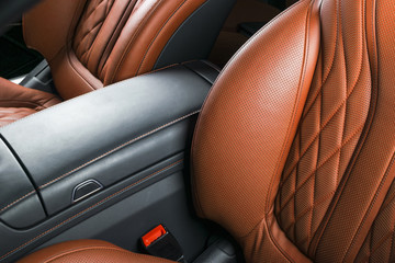 Modern Luxury car inside. Interior of prestige modern car. Comfortable leather brown seats. Orange perforated leather cockpit. Automatic transmission. Modern car interior details