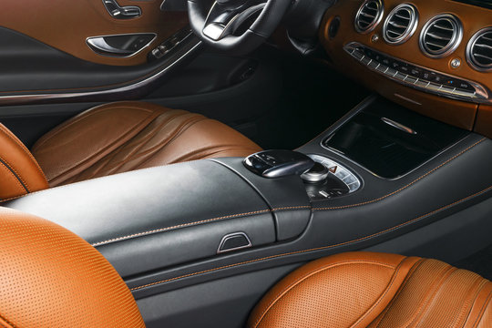 Modern Luxury car inside. Interior of prestige modern car. Comfortable leather seats. Orange perforated leather cockpit. Steering wheel and dashboard. automatic gear stick shift. Car interior