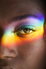 Rainbow light over eye of beautiful woman, close up