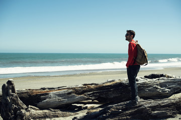 Retrato de hombre joven vestido de rojo frente a paisaje de playa minimalista con un amplio cielo azul.