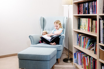 blondes mädchen beim lesen mit puppe