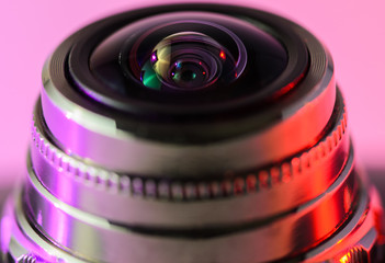 Close-up camera lens with purple-red illumination. Horizontal photo.
