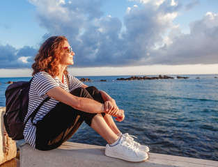 portrait of a beautiful happy young woman sitting on the background of the sea and a beautiful...