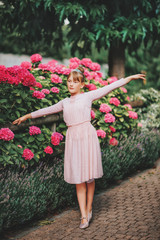 Little ballerina girl dancing in hydrangea garden, wearing tutu dress