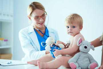 Female doctor is listening kid with a stethoscope in clinic