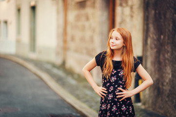 Outdoor fashion portrait of happy red-haired girl