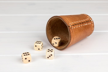 dice cup with cube on white wooden background