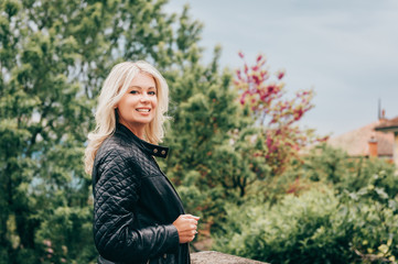 Outdoor portrait of beautiful blond woman wearing black leather jacket