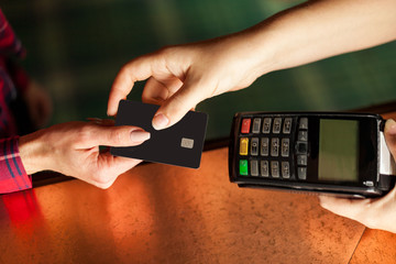 Customer gives credit card to cashier. Woman hands holding. View from top