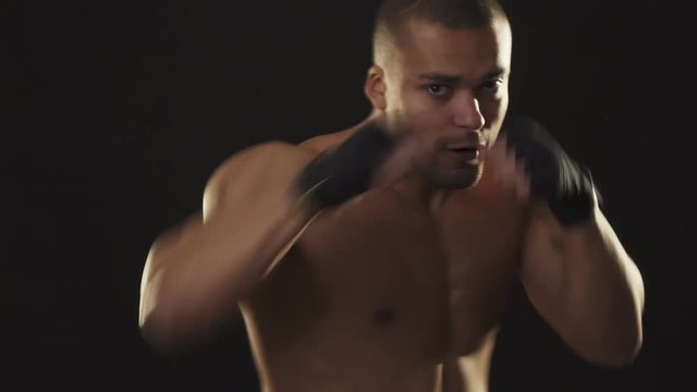 Young handsome African fighter shadow boxing on black background