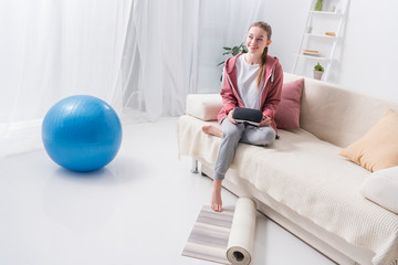 girl holding virtual reality headset and looking away at home