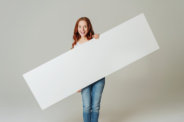 Cheerful woman standing with blank white board