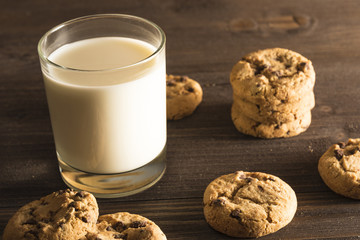 A glass of milk and cookies on a dark wooden background