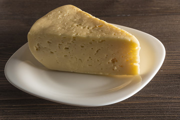  Cheese on a white plate on a dark wooden background