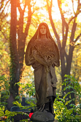 A fragment of ancient figure of the Virgin in the old cemetery as a symbol of love and intercession of mankind after death in the kingdom of eternity in a golden glow.