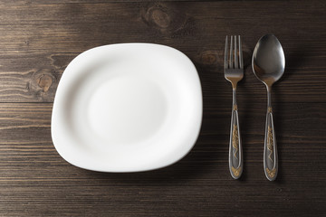 Fork, spoon and white plate on a dark wooden background