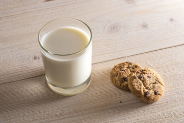 Glass of milk and cookies on a light wooden background