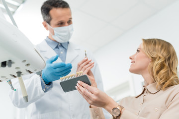 Doctor showing tooth implants to female patient in modern dental clinic