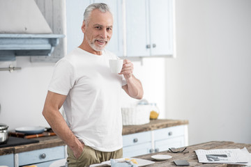 Have free time. Positive delighted male person smiling while looking forward and keeping right hand in the pocket