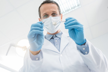 Dentist checking patient teeth with mirror in modern clinic