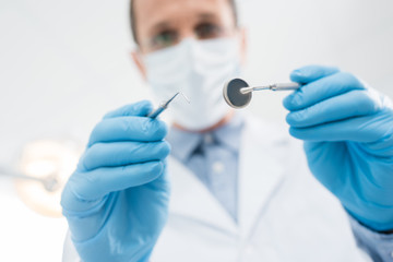 Doctor checking patient teeth with mirror in modern dental clinic